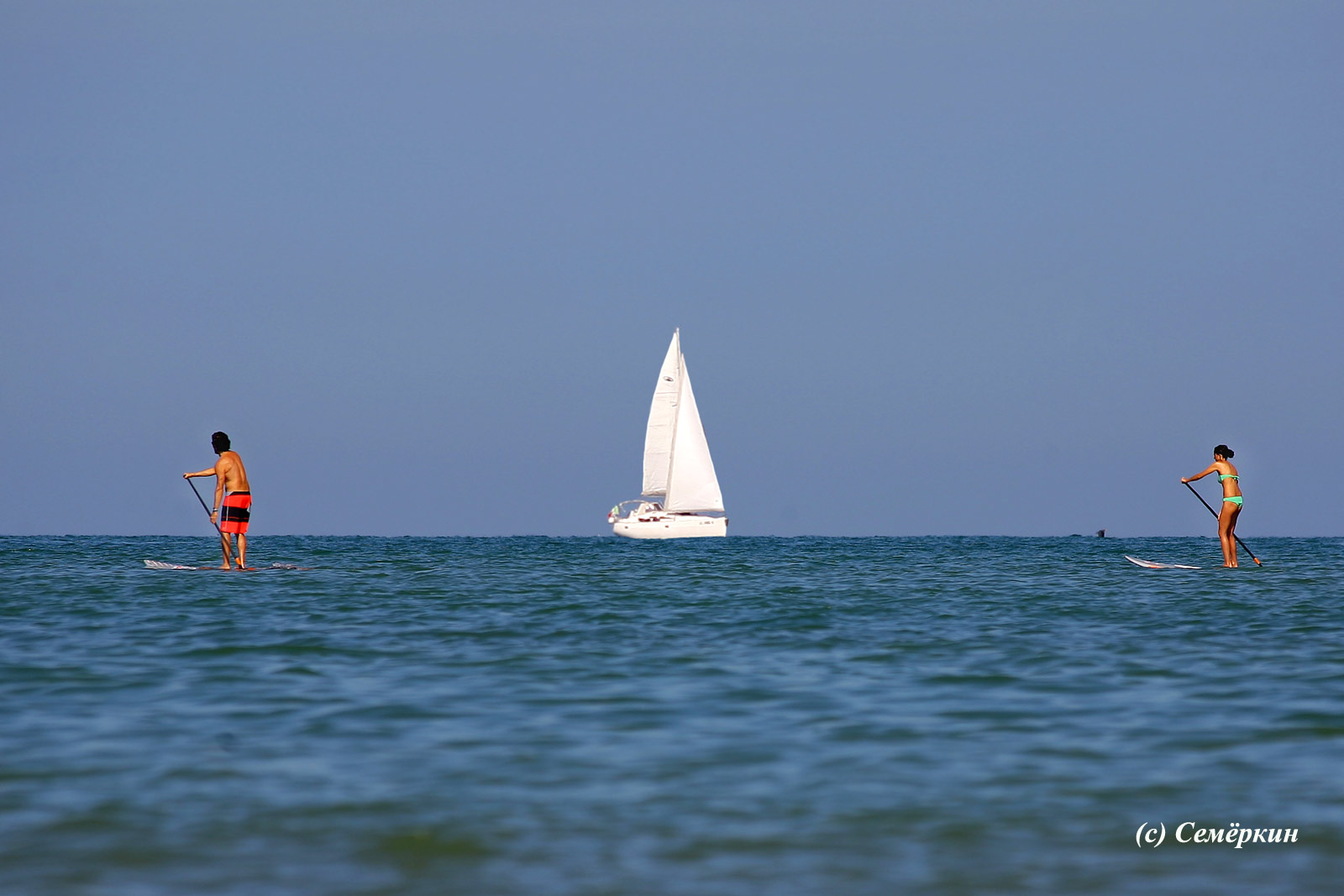 Римини - море, яхта и идущие по воде мужчина и женщина